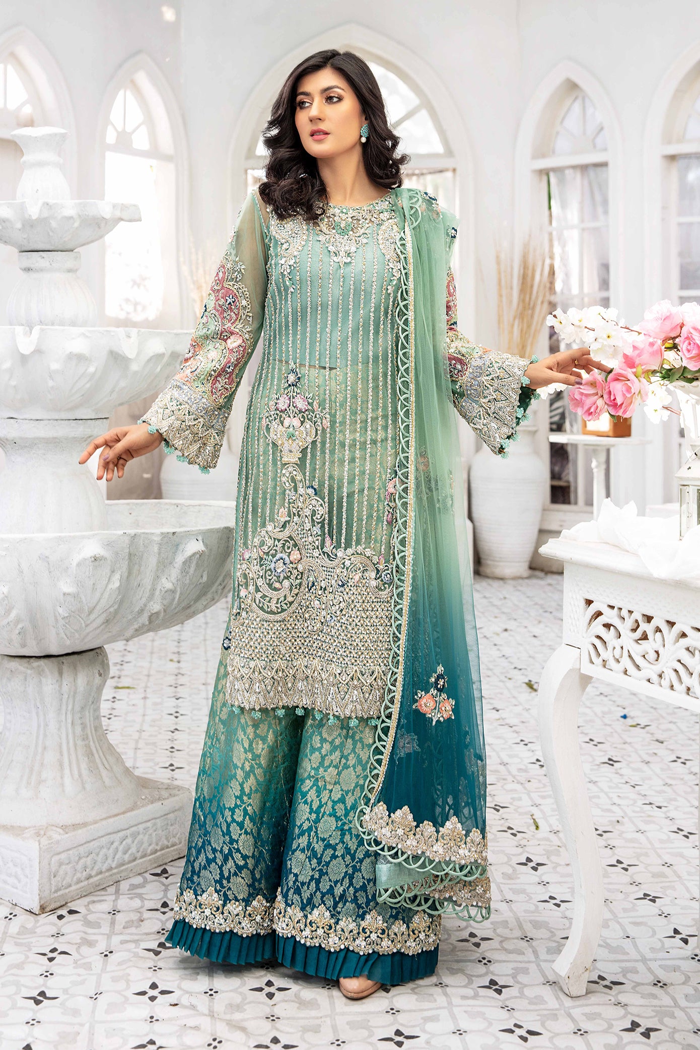 A beautiful turquoise blue double shaded Pakistani formal dress with intricate silver work on the bodice and sleeves. The dress features a lovely dupatta that complements the elegant design. Perfect for formal events and special occasions, this dress showcases traditional Pakistani style with its mesmerizing beauty and charm.