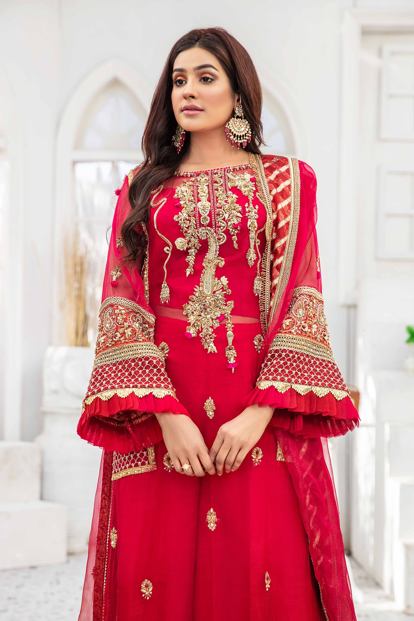 A beautiful Pakistani formal dress in shades of maroon and pink, with intricate gold work adorning the bodice, sleeves, and hemline. The dress features a flattering silhouette and is perfect for formal occasions.