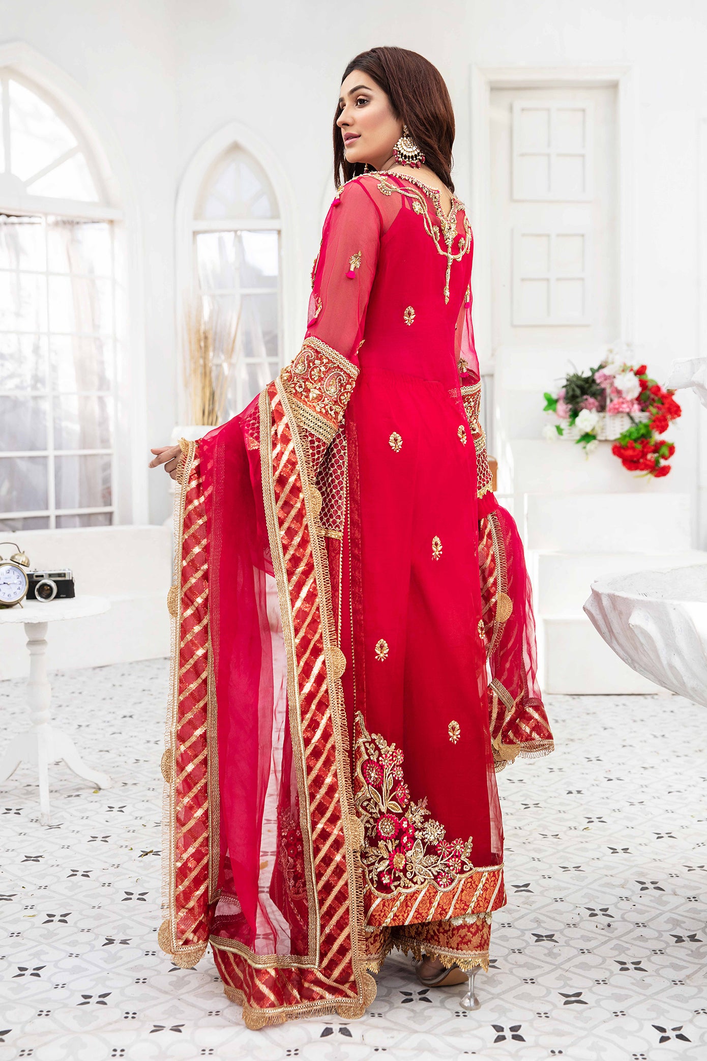 A beautiful Pakistani formal dress in shades of maroon and pink, with intricate gold work adorning the bodice, sleeves, and hemline. The dress features a flattering silhouette and is perfect for formal occasions.