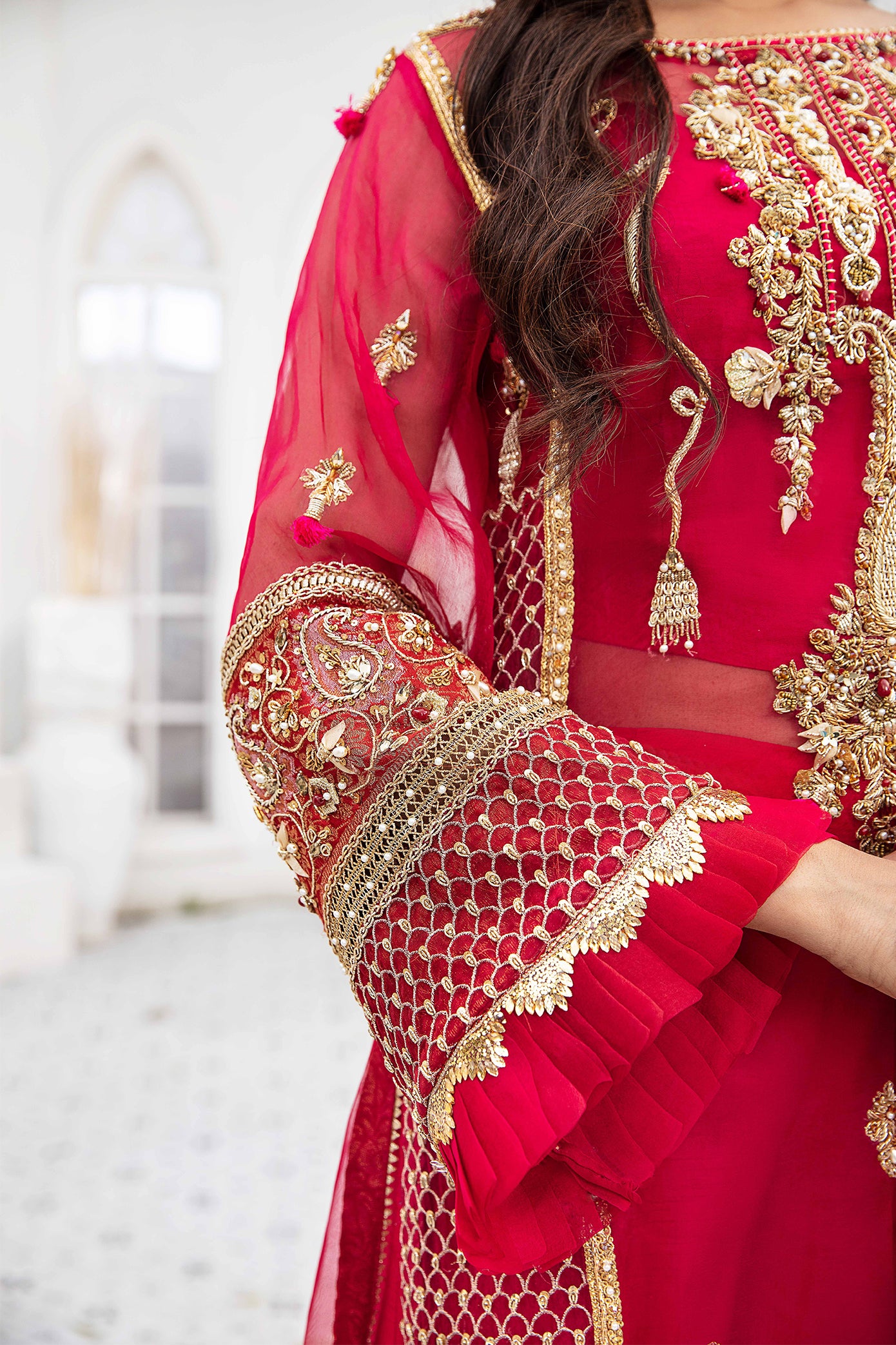 A beautiful Pakistani formal dress in shades of maroon and pink, with intricate gold work adorning the bodice, sleeves, and hemline. The dress features a flattering silhouette and is perfect for formal occasions.