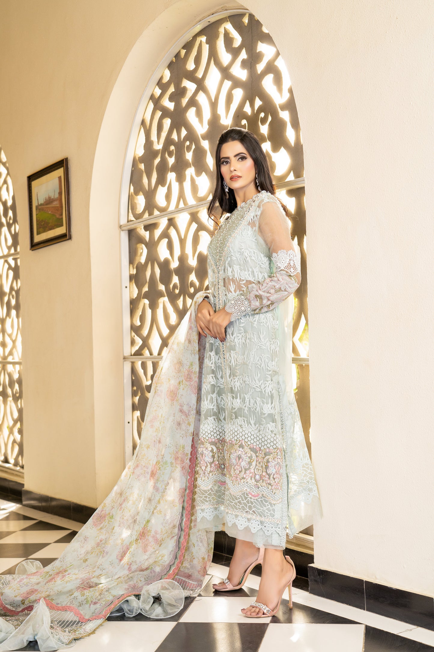A Pakistani luxury Pret outfit consisting of a white shirt with intricate embroidery work, featuring pink fabric work at the bottom. The outfit is paired with a pink and white dupatta with flower prints.