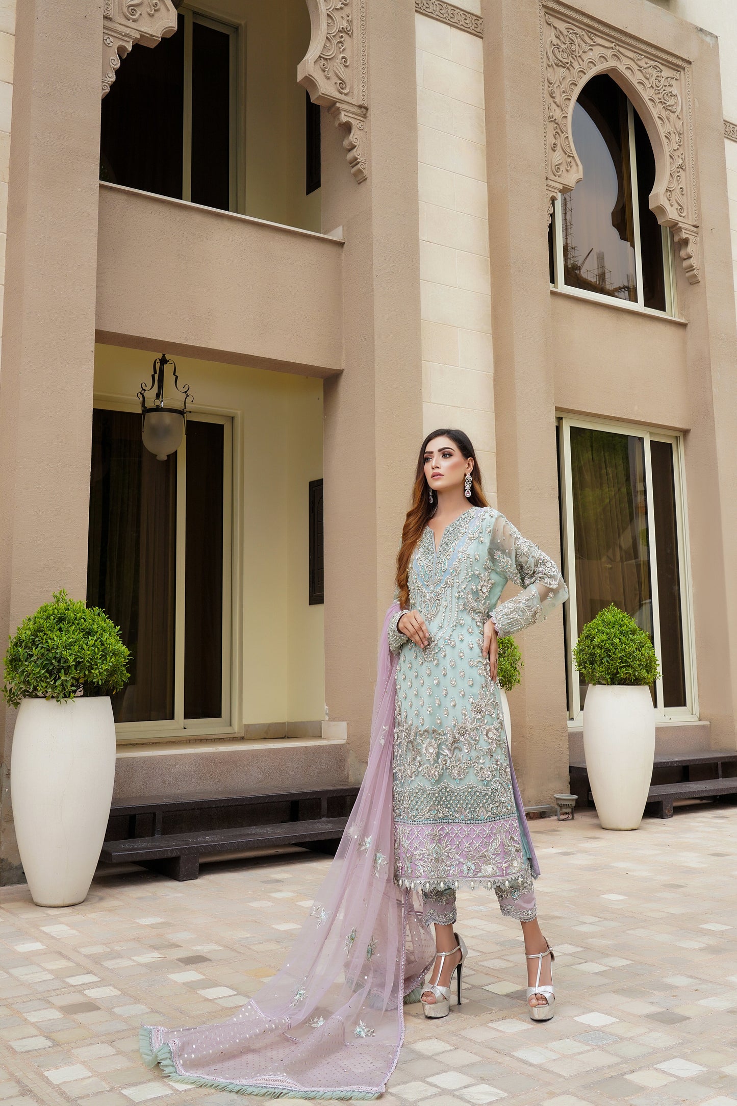 Stunning Pakistani formal dress in turquoise and violet colors, featuring a fitted bodice and flowing skirt, with a complementary pink dupatta. Perfect for formal occasions, this dress is eye-catching and unique with its beautiful color combination.