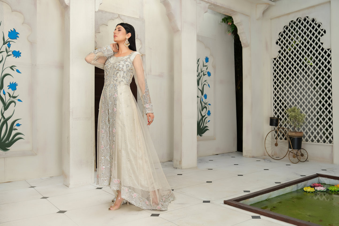 light nude Pakistani formal dress with intricate silver work. The dress features delicate embroidery, sequins, and other hand-crafted designs that create a unique and beautiful pattern on the fabric. It has a long, flowing silhouette that drapes beautifully on the body and full-length sleeves with silver work detailing. The neckline is also adorned with silver work embellishments, adding glamour and sophistication to the dress.