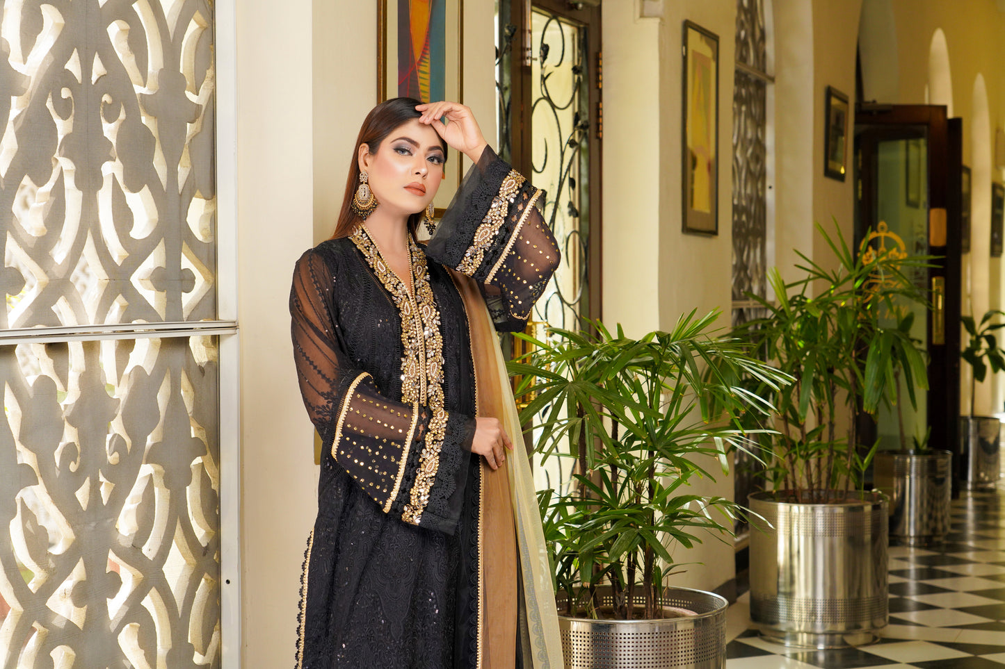 Luxurious black and gold Pakistani dress with intricate gold work around neckline and sleeves. Flattering fitted bodice and flowing skirt. Elegant v-neckline and long sleeves with stunning gold embroidery. Perfect for special occasions exuding confidence, power, and sophistication.