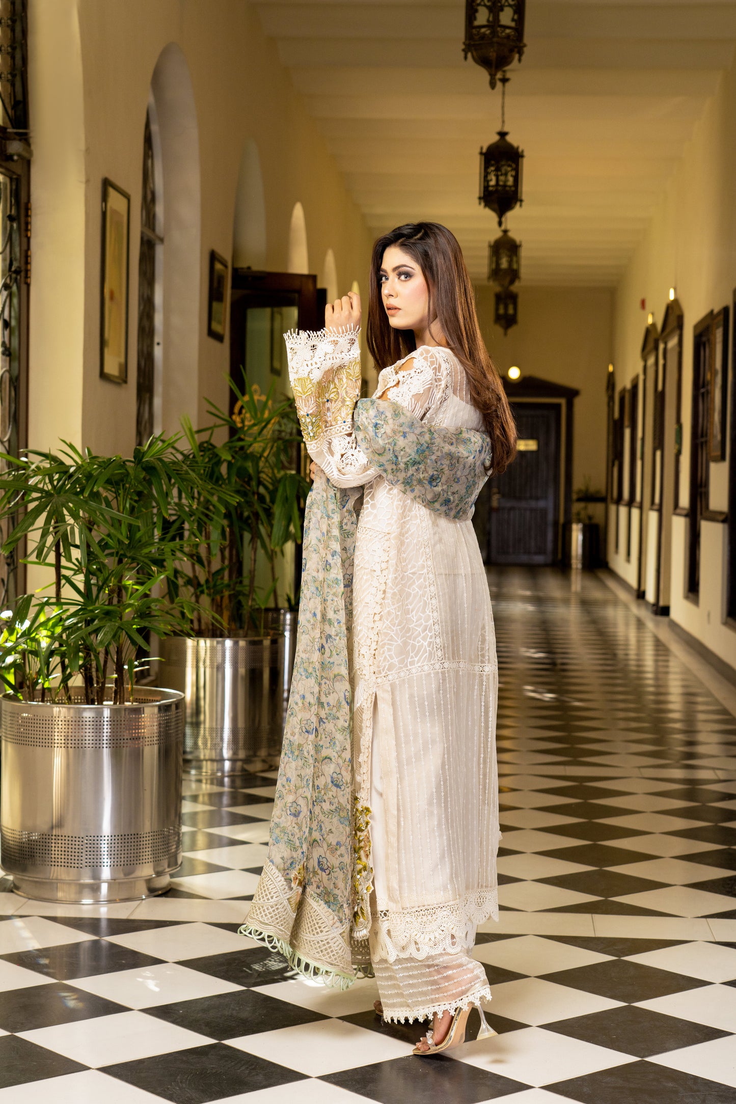 Off-white luxury Pret Pakistani dress with intricate gold work embellishments. Fitted bodice Voluminous skirt with swirling gold work pattern. Paired with a printed designed dupatta featuring floral and paisley prints in gold and off-white, finished with a matching gold trim