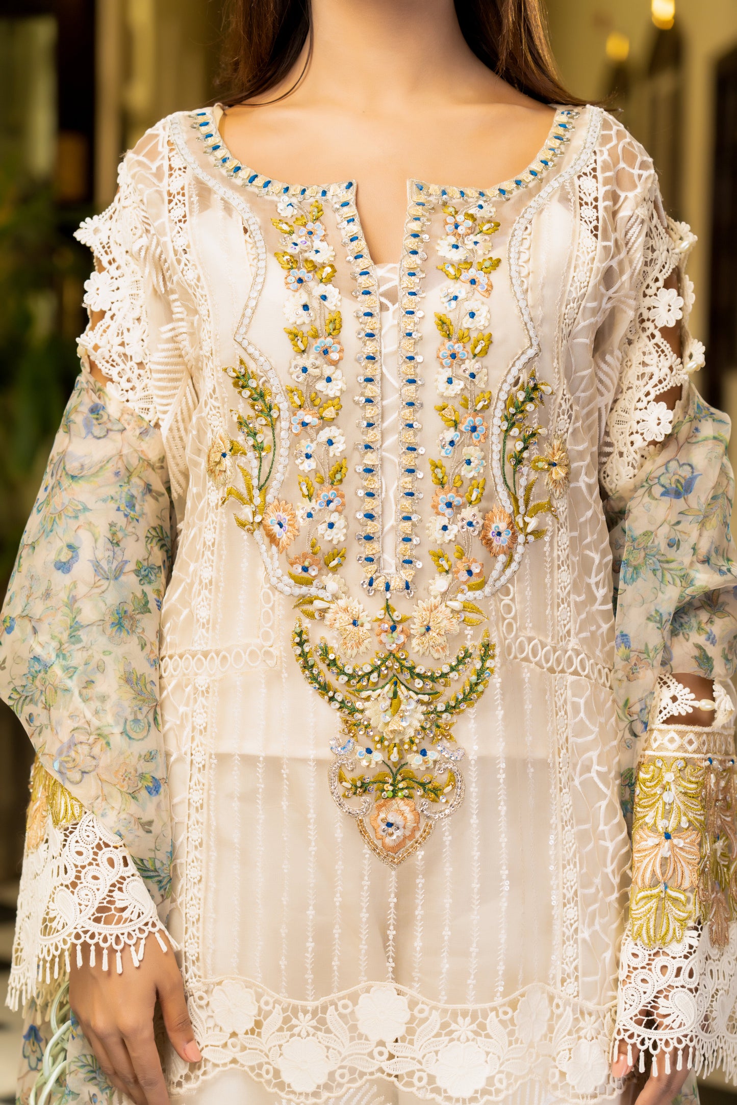 Off-white luxury Pret Pakistani dress with intricate gold work embellishments. Fitted bodice Voluminous skirt with swirling gold work pattern. Paired with a printed designed dupatta featuring floral and paisley prints in gold and off-white, finished with a matching gold trim