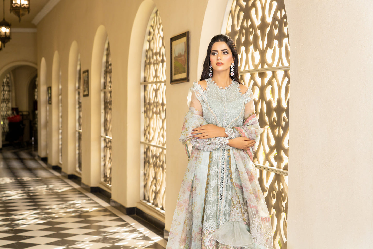 A Pakistani luxury Pret outfit consisting of a white shirt with intricate embroidery work, featuring pink fabric work at the bottom. The outfit is paired with a pink and white dupatta with flower prints.