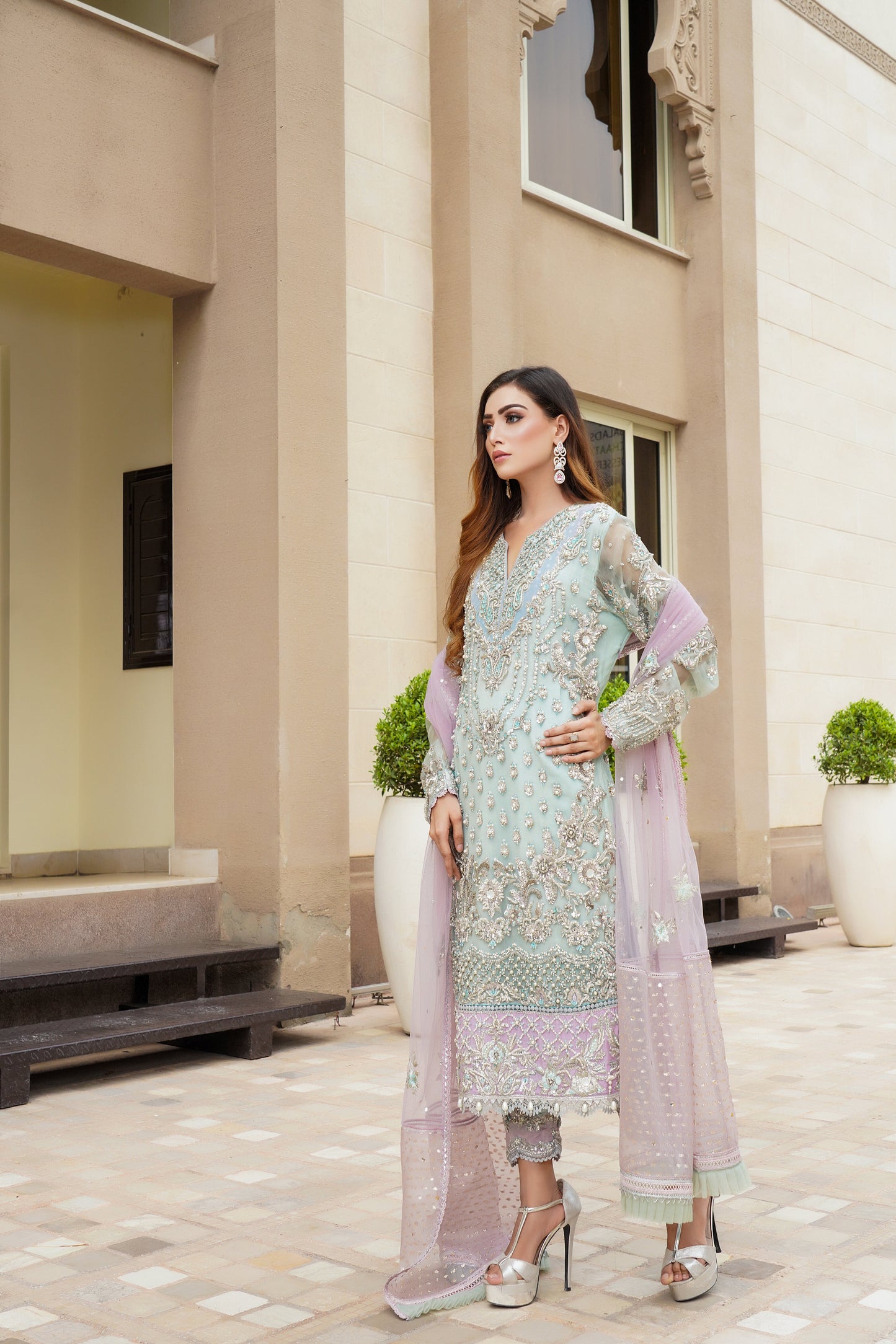 Stunning Pakistani formal dress in turquoise and violet colors, featuring a fitted bodice and flowing skirt, with a complementary pink dupatta. Perfect for formal occasions, this dress is eye-catching and unique with its beautiful color combination.