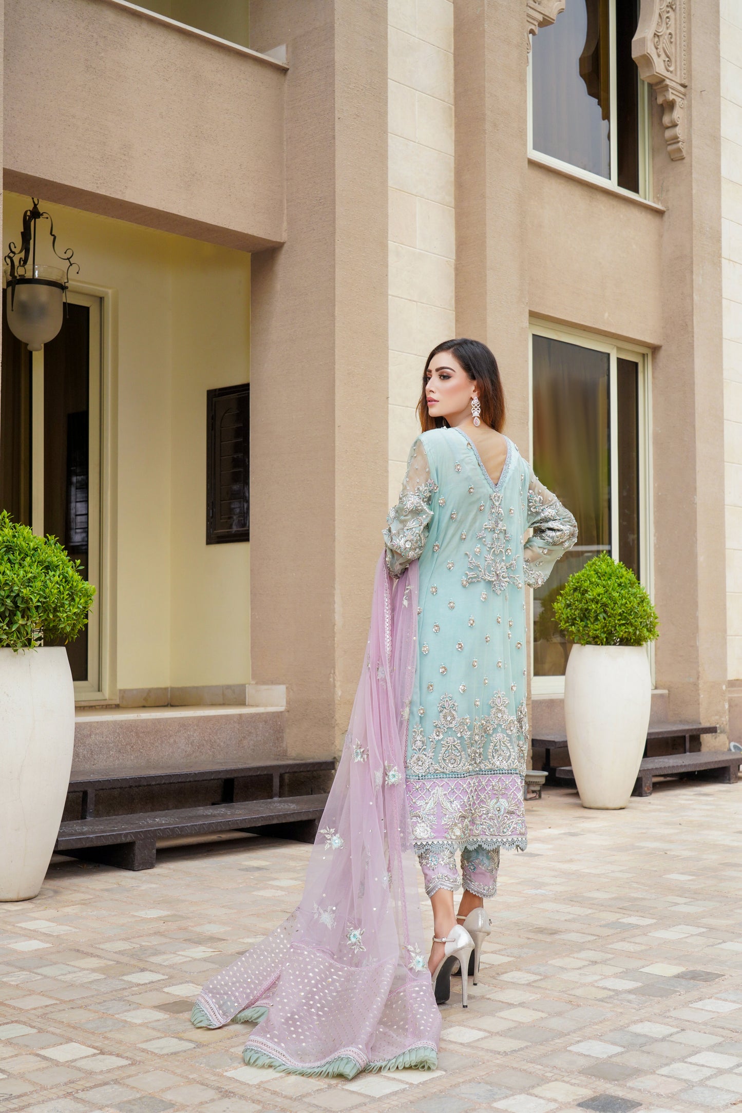 Stunning Pakistani formal dress in turquoise and violet colors, featuring a fitted bodice and flowing skirt, with a complementary pink dupatta. Perfect for formal occasions, this dress is eye-catching and unique with its beautiful color combination.