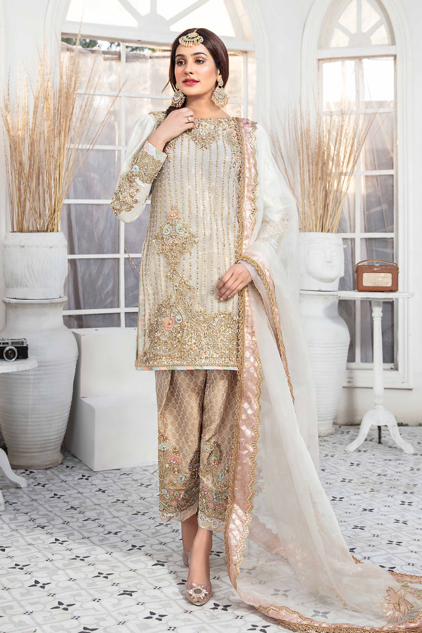 Elegant light gold Pakistani formal dress - Featuring intricate darker gold embroidery work that flows seamlessly down the length of the dress. Completed with a stunning white and rose gold dupatta that adds an extra layer of sophistication to the overall design. Perfect for any formal occasion, this dress is sure to impress with its attention to detail and elegant design