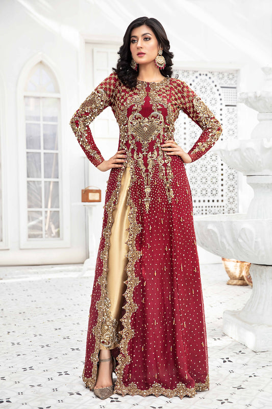 A Red and Gold Pakistani Formal Dress with intricate gold work on the sleeves, neckline, and hemline. The dress has a long flowing silhouette in a rich red color and is paired with a comfortable gold trouser with gold work on the hemline. The dress exudes elegance and sophistication, making it perfect for special occasions. The wearer is standing with a confident posture, showcasing the regal and luxurious look of the dress.