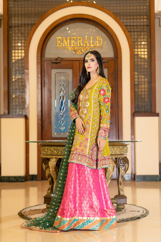 A stunning Pakistani bridal dress in yellow and pink with a green dupatta. Intricate gold handwork with embroidery, sequins, and beadwork in floral and paisley patterns. Fitted bodice with a sweetheart neckline and long sleeves, and a flowing skirt with a wide flare. The matching dupatta is draped over the head, adding a regal touch. Perfect for brides who want to make a bold and vibrant statement.