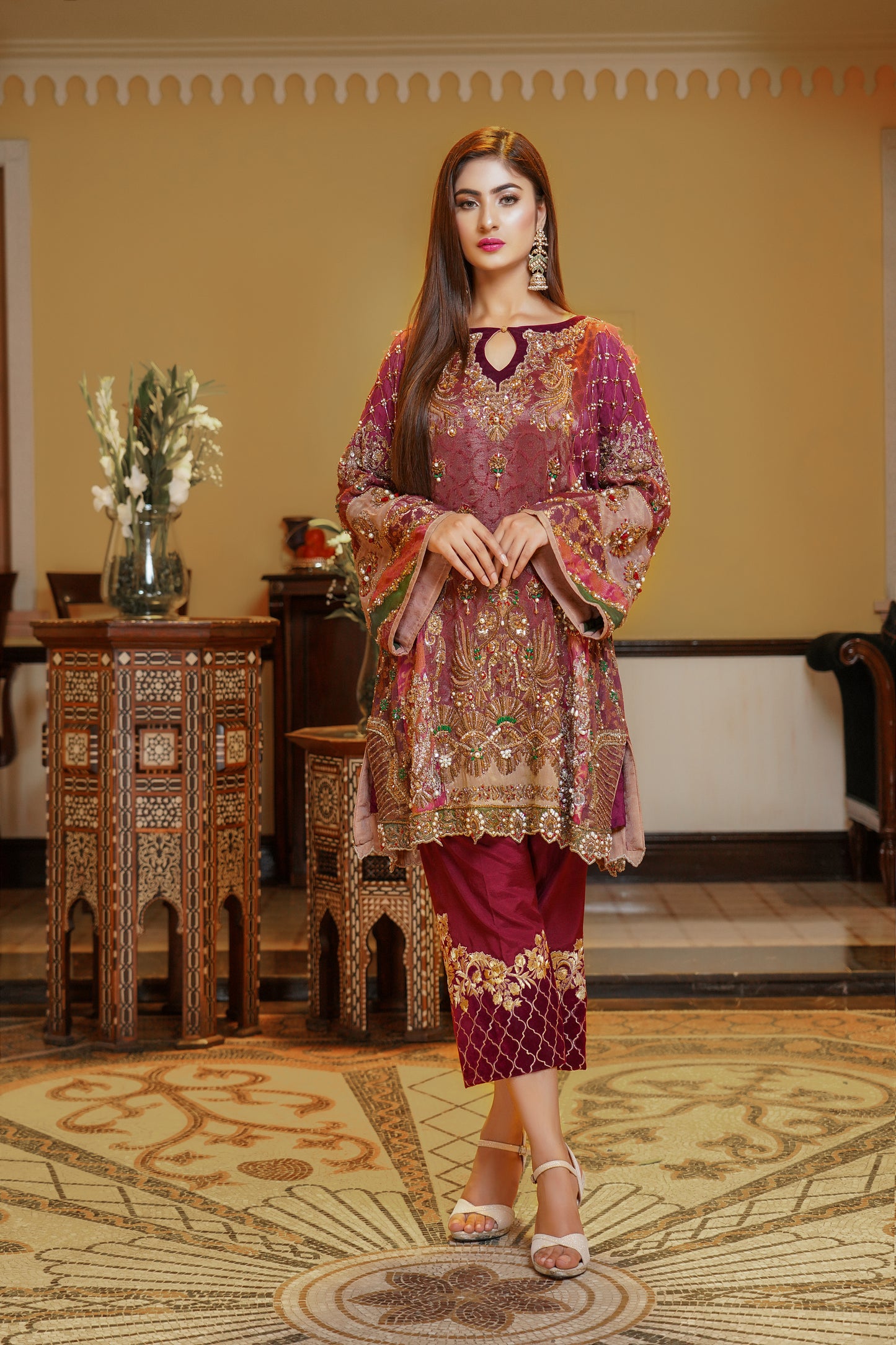 Stunning maroon and gold Pakistani formal dress, This dress features intricate gold embroidery on rich red fabric, with orange and green detailing on the sleeves that beautifully complements the overall design. Perfect for any formal occasion, this dress is a true work of art that exudes confidence and elegance