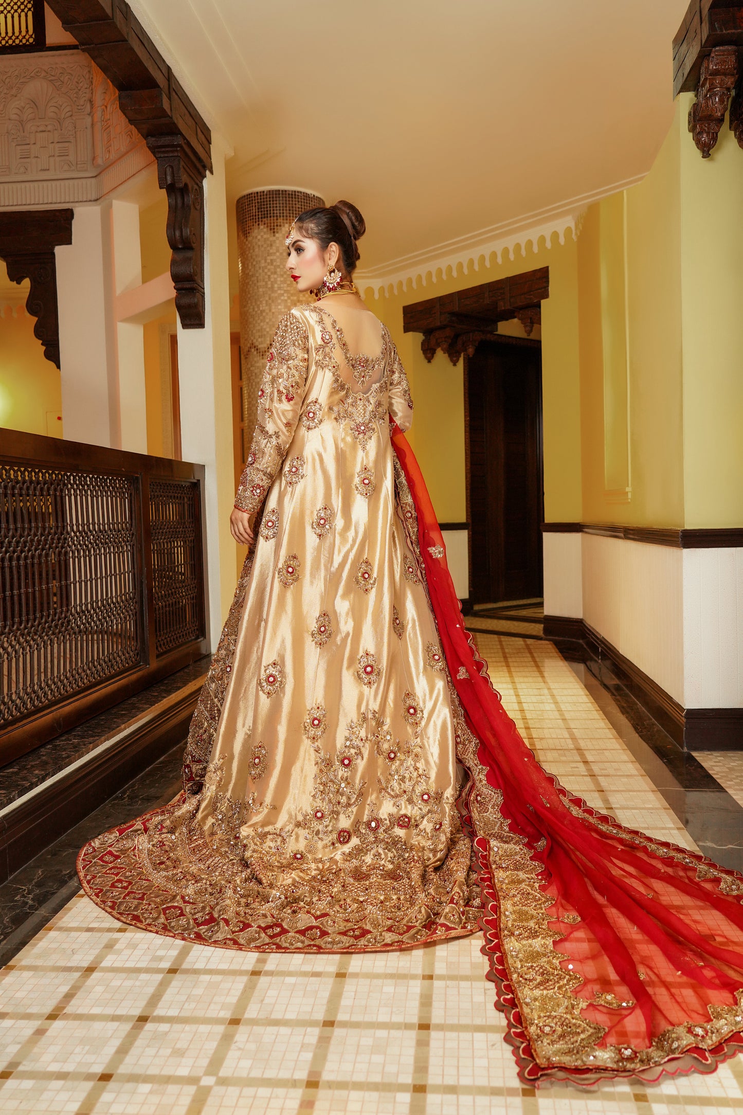 Pakistani dress with red dupatta. Predominantly gold with intricate gold work embellishments, heavy gold border with touch of red on skirt. Fitted bodice with flared skirt. Matching red dupatta with delicate gold border. Traditional and elegant outfit with a touch of color for brides.