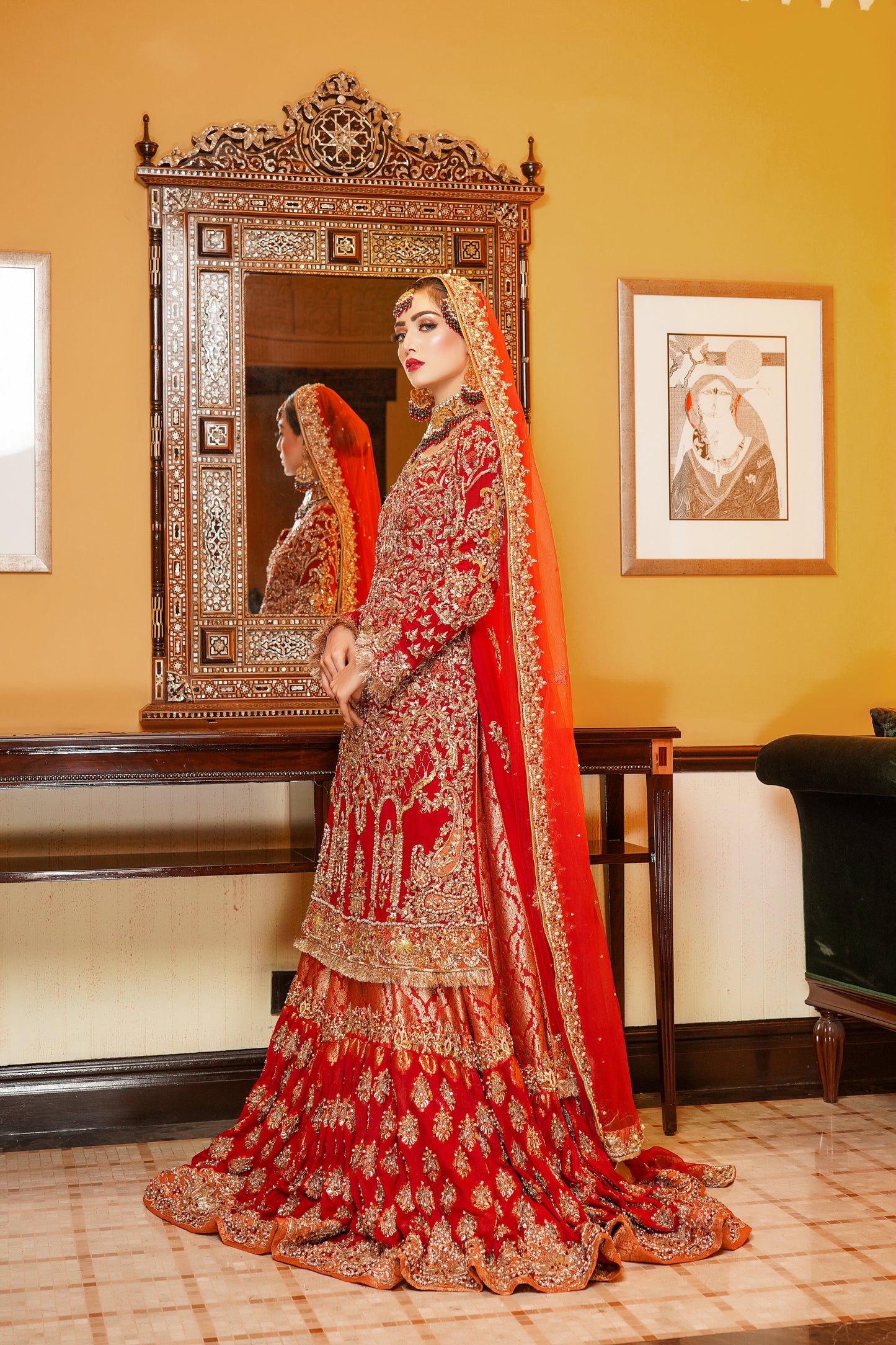 Red and gold Pakistani bridal dress. The dress is a beautiful combination of vibrant red and rich gold. The bodice of the dress features intricate gold embroidery and beadwork, while the skirt is adorned with a heavy gold border. The dress has a fitted bodice with a flared skirt that flows gracefully. The outfit is completed with a matching red dupatta that is embellished with gold embroidery. 