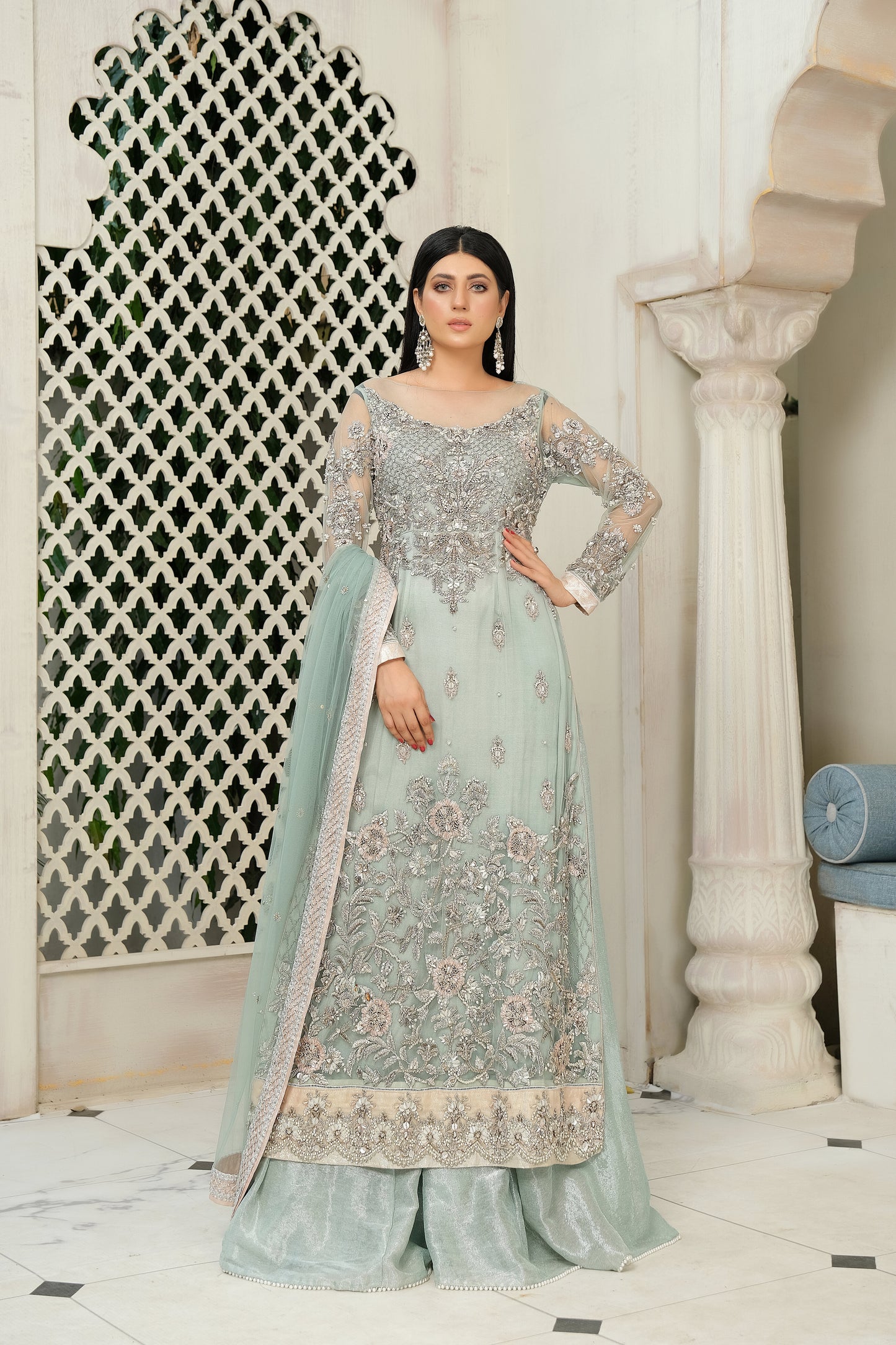 A stunning combination of blue and silver embroidery on a flowing bridal gown. The intricate silver work adorns the bodice and cascades down to the hemline, while the blue fabric provides a beautiful backdrop. The dress also features a flowing dupatta with delicate silver details, completing the elegant bridal look.