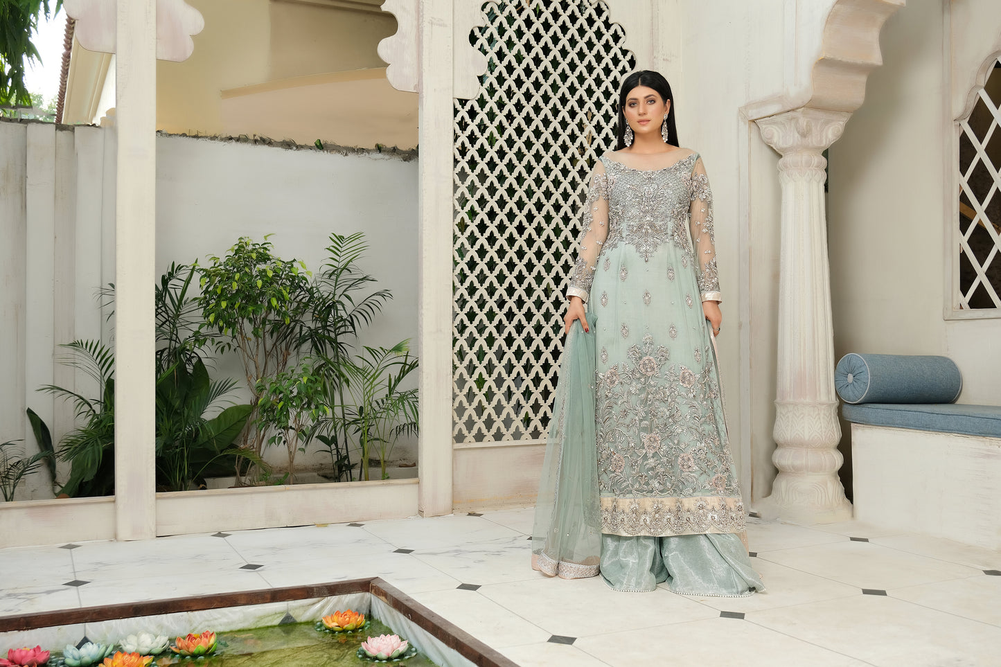 A stunning combination of blue and silver embroidery on a flowing bridal gown. The intricate silver work adorns the bodice and cascades down to the hemline, while the blue fabric provides a beautiful backdrop. The dress also features a flowing dupatta with delicate silver details, completing the elegant bridal look.