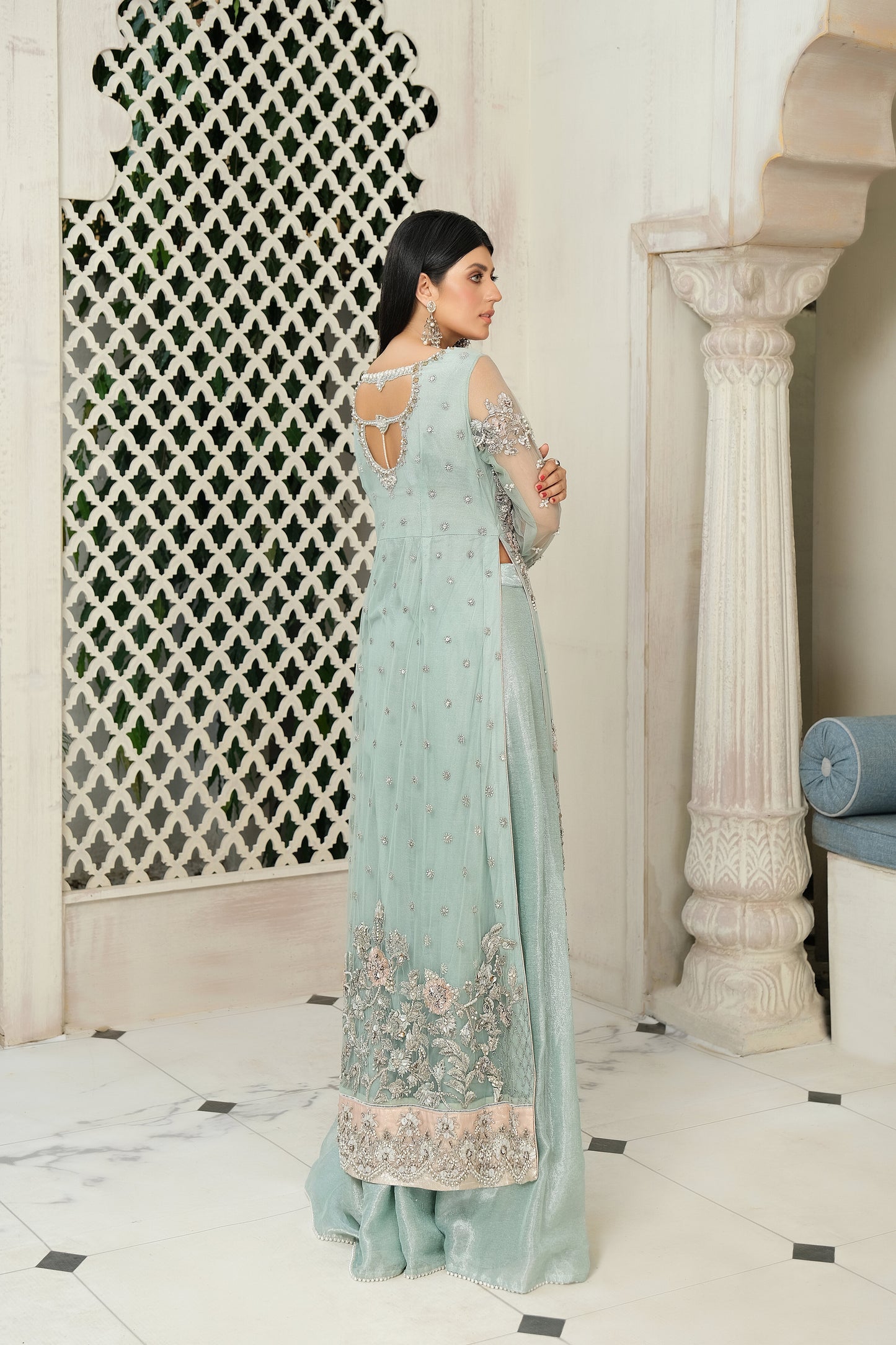 A stunning combination of blue and silver embroidery on a flowing bridal gown. The intricate silver work adorns the bodice and cascades down to the hemline, while the blue fabric provides a beautiful backdrop. The dress also features a flowing dupatta with delicate silver details, completing the elegant bridal look.