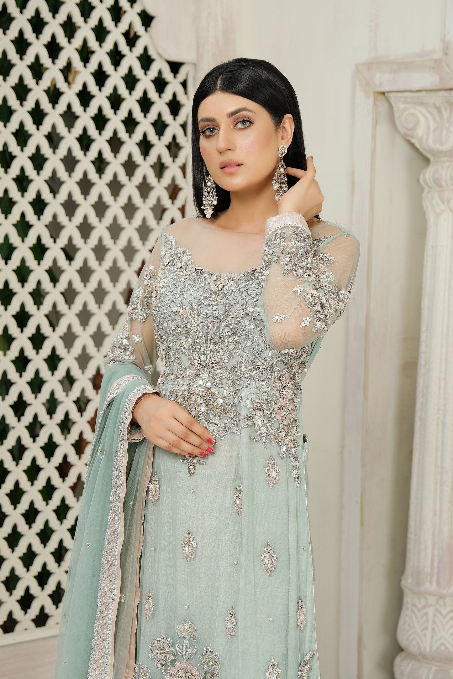 A stunning combination of blue and silver embroidery on a flowing bridal gown. The intricate silver work adorns the bodice and cascades down to the hemline, while the blue fabric provides a beautiful backdrop. The dress also features a flowing dupatta with delicate silver details, completing the elegant bridal look.