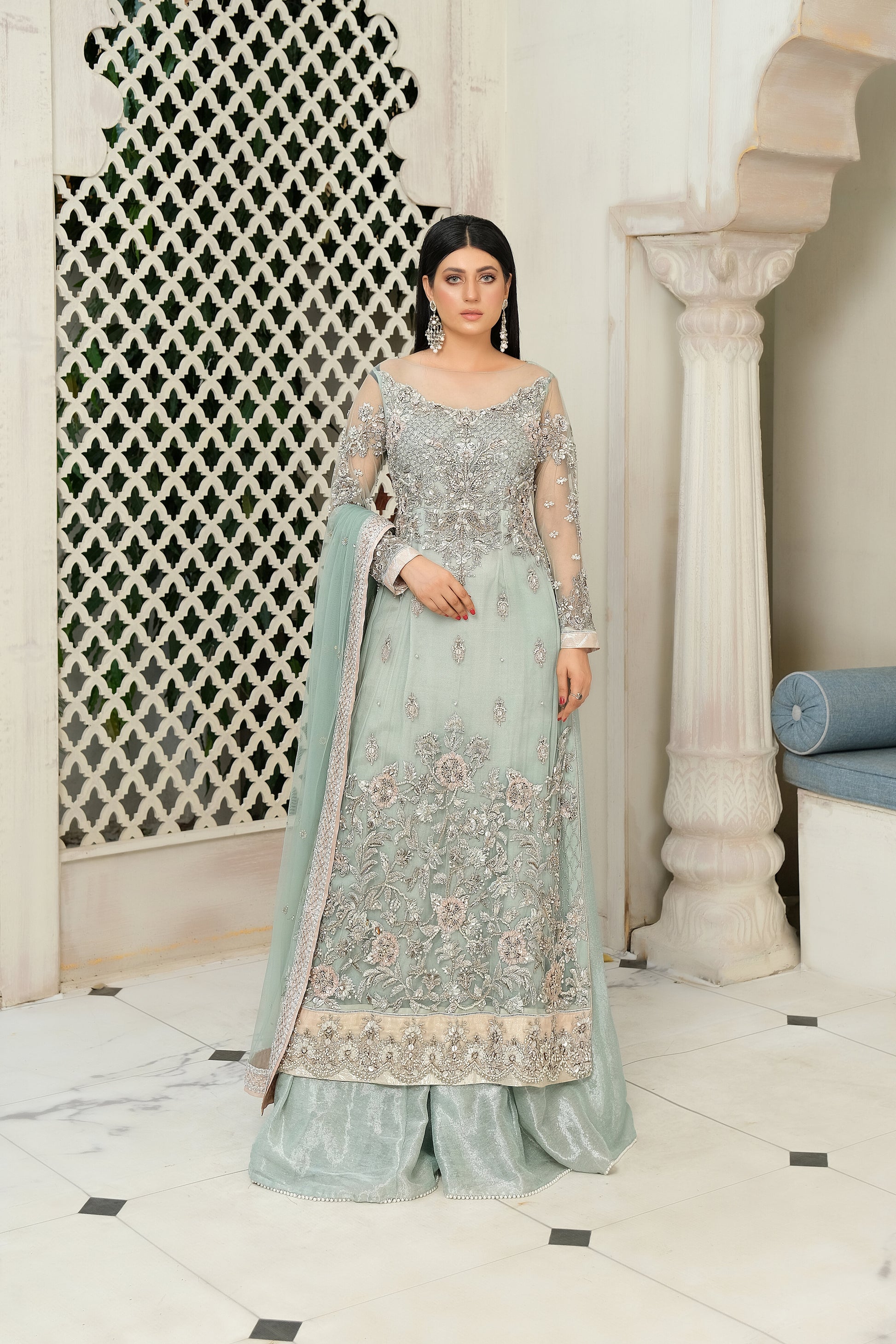 A stunning combination of blue and silver embroidery on a flowing bridal gown. The intricate silver work adorns the bodice and cascades down to the hemline, while the blue fabric provides a beautiful backdrop. The dress also features a flowing dupatta with delicate silver details, completing the elegant bridal look.