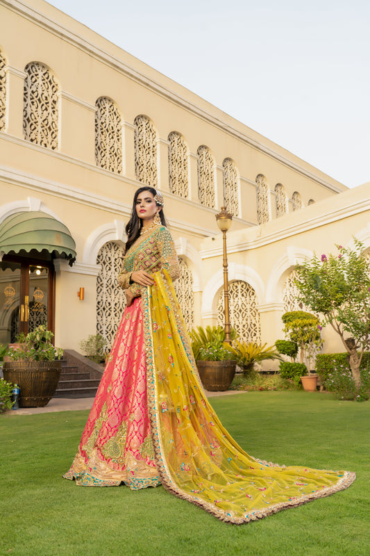 Pink and green Pakistani bridal dress with yellow dupatta. Intricate work embellishments, gold embroidery and beadwork on pink bodice, heavy border on green skirt. Flowing silhouette with fitted bodice and flared skirt. Vibrant yellow dupatta with delicate gold thread work. Perfect for Pakistani brides looking for colorful wedding outfits.