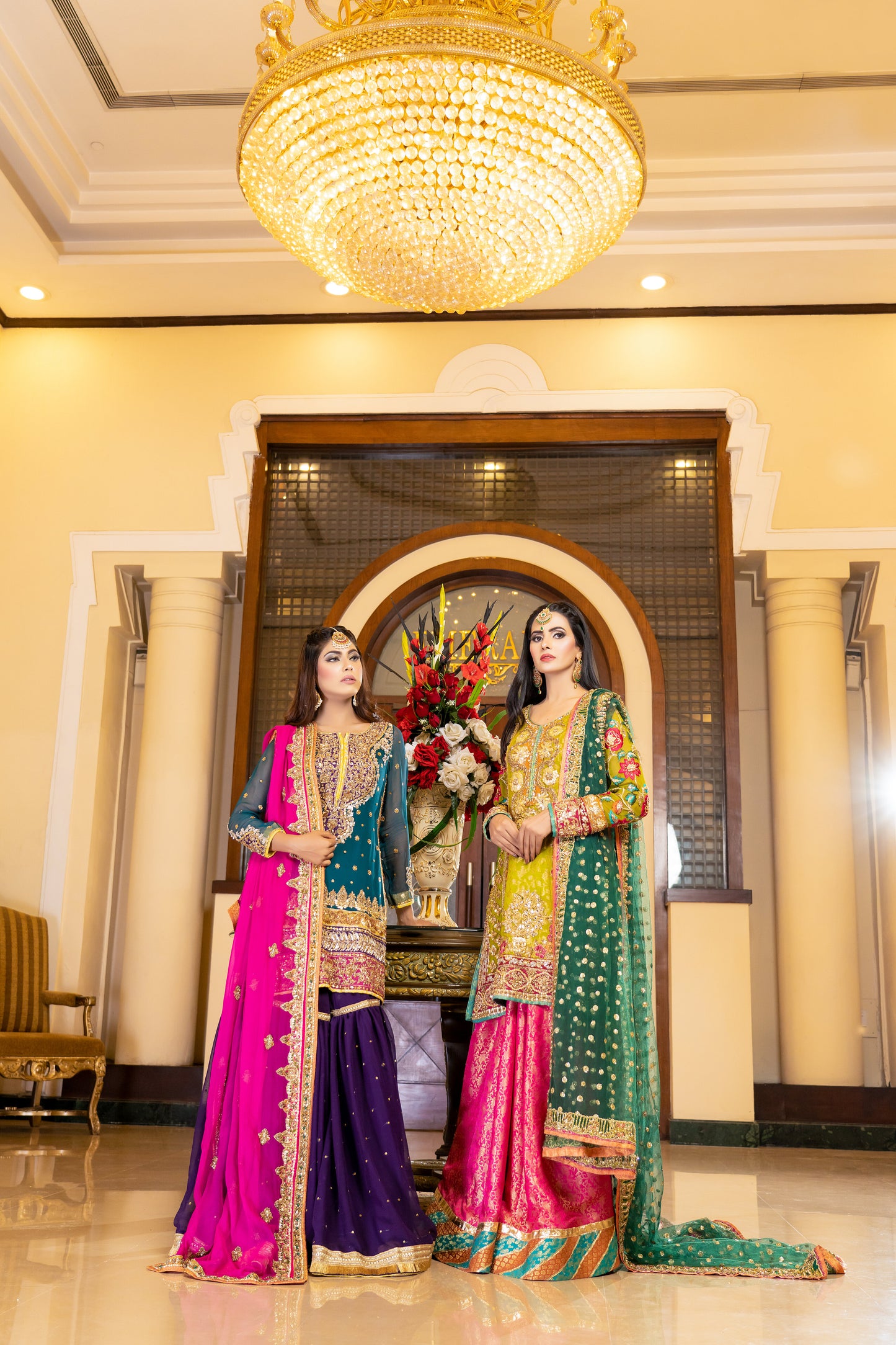 A stunning Pakistani bridal dress in yellow and pink with a green dupatta. Intricate gold handwork with embroidery, sequins, and beadwork in floral and paisley patterns. Fitted bodice with a sweetheart neckline and long sleeves, and a flowing skirt with a wide flare. The matching dupatta is draped over the head, adding a regal touch. Perfect for brides who want to make a bold and vibrant statement.