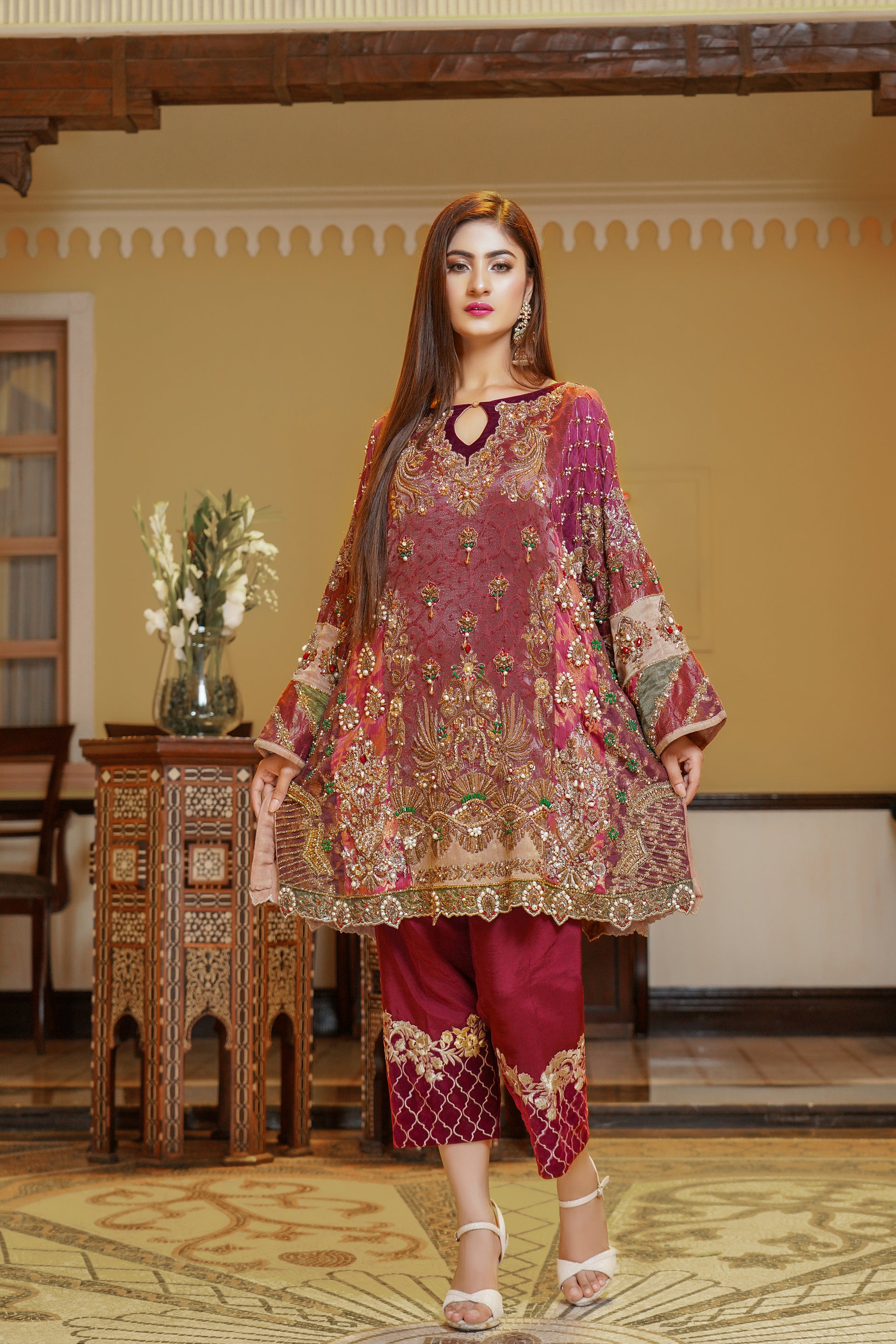 Stunning maroon and gold Pakistani formal dress, This dress features intricate gold embroidery on rich red fabric, with orange and green detailing on the sleeves that beautifully complements the overall design. Perfect for any formal occasion, this dress is a true work of art that exudes confidence and elegance