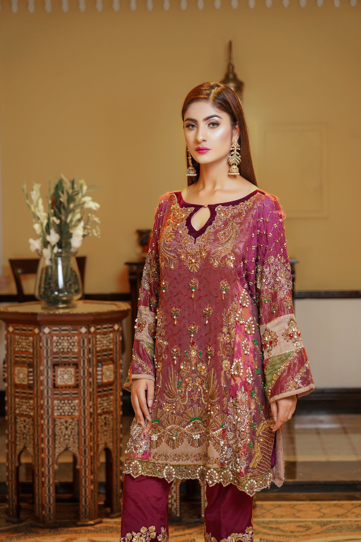 Stunning maroon and gold Pakistani formal dress, This dress features intricate gold embroidery on rich red fabric, with orange and green detailing on the sleeves that beautifully complements the overall design. Perfect for any formal occasion, this dress is a true work of art that exudes confidence and elegance