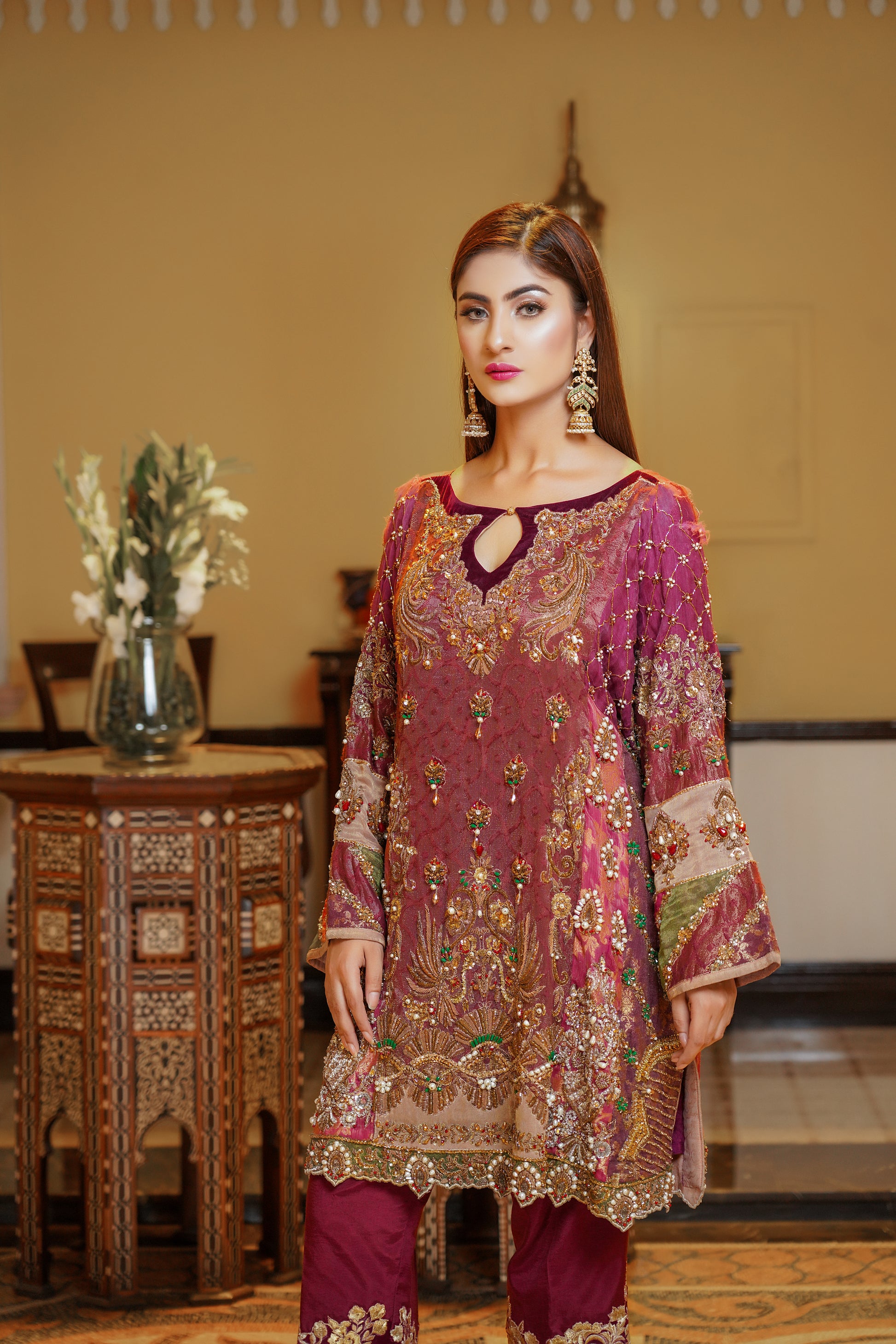 Stunning maroon and gold Pakistani formal dress, This dress features intricate gold embroidery on rich red fabric, with orange and green detailing on the sleeves that beautifully complements the overall design. Perfect for any formal occasion, this dress is a true work of art that exudes confidence and elegance