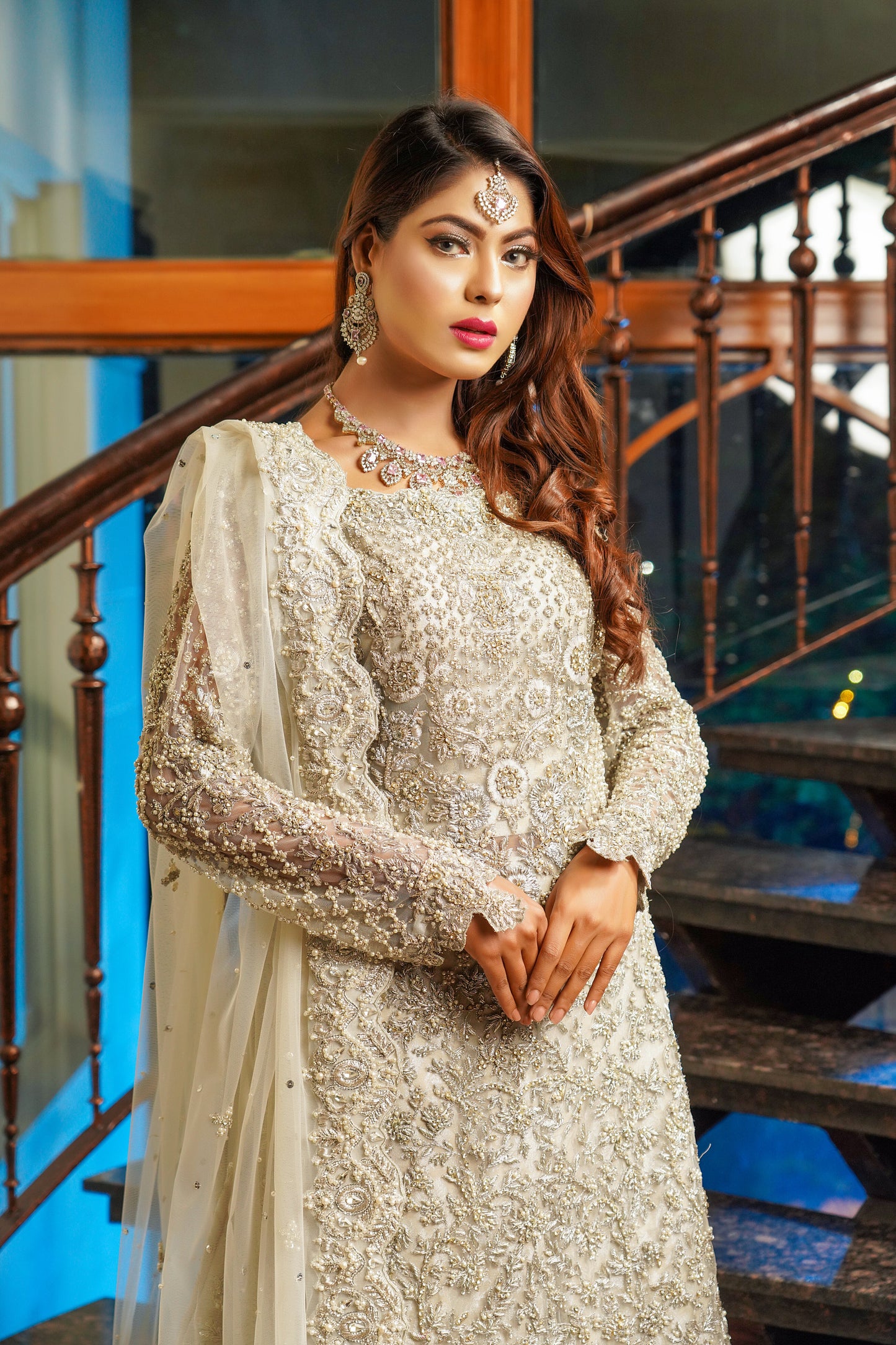 Silver and grey Pakistani bridal dress. The dress features intricate silver work embellishments on a soft grey fabric, creating an elegant and sophisticated look. The fitted bodice has silver embroidery and beadwork, while the flowing skirt has a heavy silver border. The outfit comes with a matching dupatta that complements the dress with delicate silver work details. 