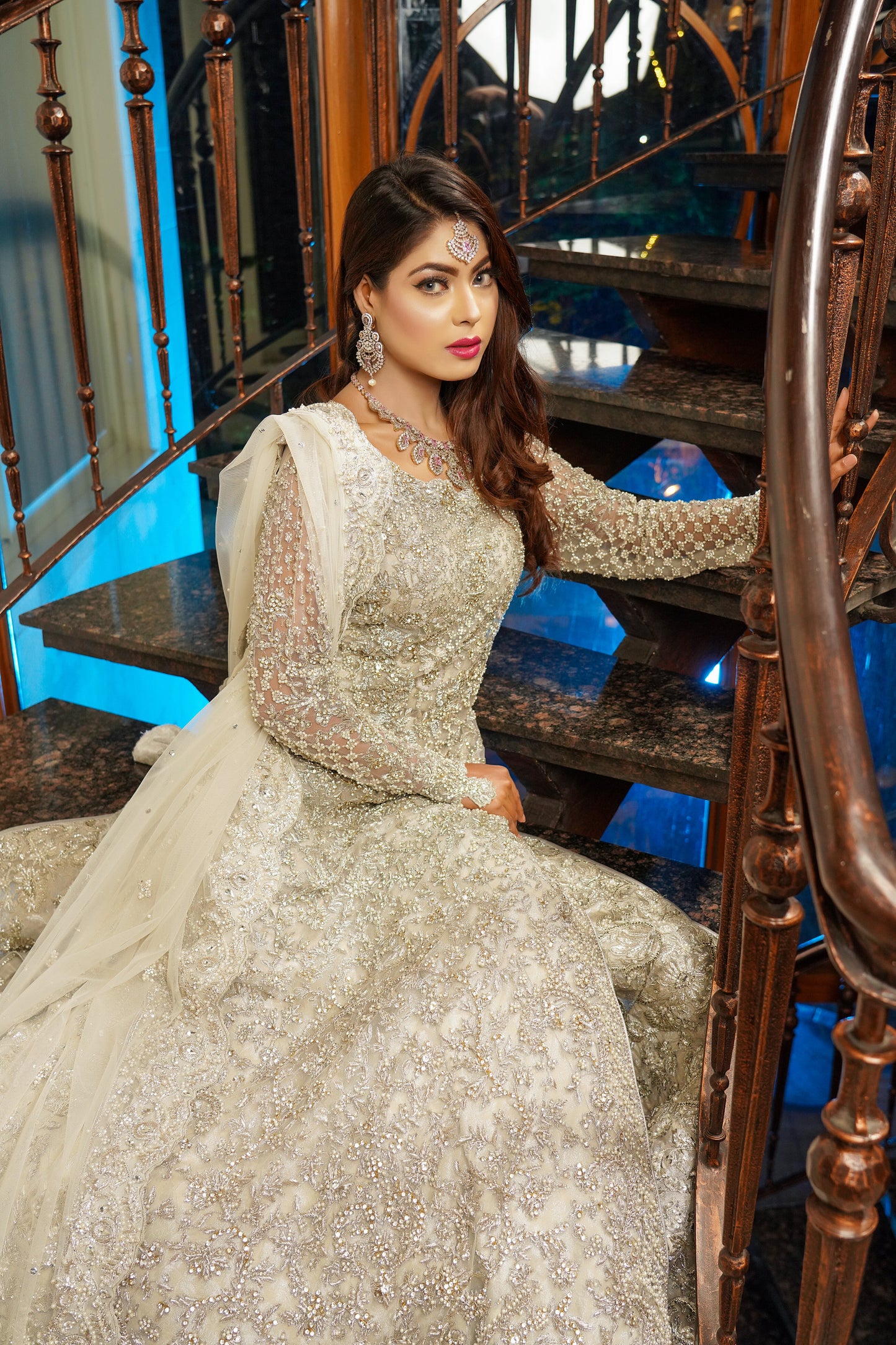 Silver and grey Pakistani bridal dress. The dress features intricate silver work embellishments on a soft grey fabric, creating an elegant and sophisticated look. The fitted bodice has silver embroidery and beadwork, while the flowing skirt has a heavy silver border. The outfit comes with a matching dupatta that complements the dress with delicate silver work details. 