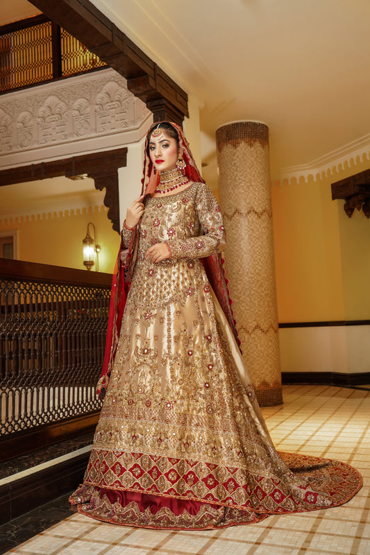 Pakistani dress with red dupatta. Predominantly gold with intricate gold work embellishments, heavy gold border with touch of red on skirt. Fitted bodice with flared skirt. Matching red dupatta with delicate gold border. Traditional and elegant outfit with a touch of color for brides.