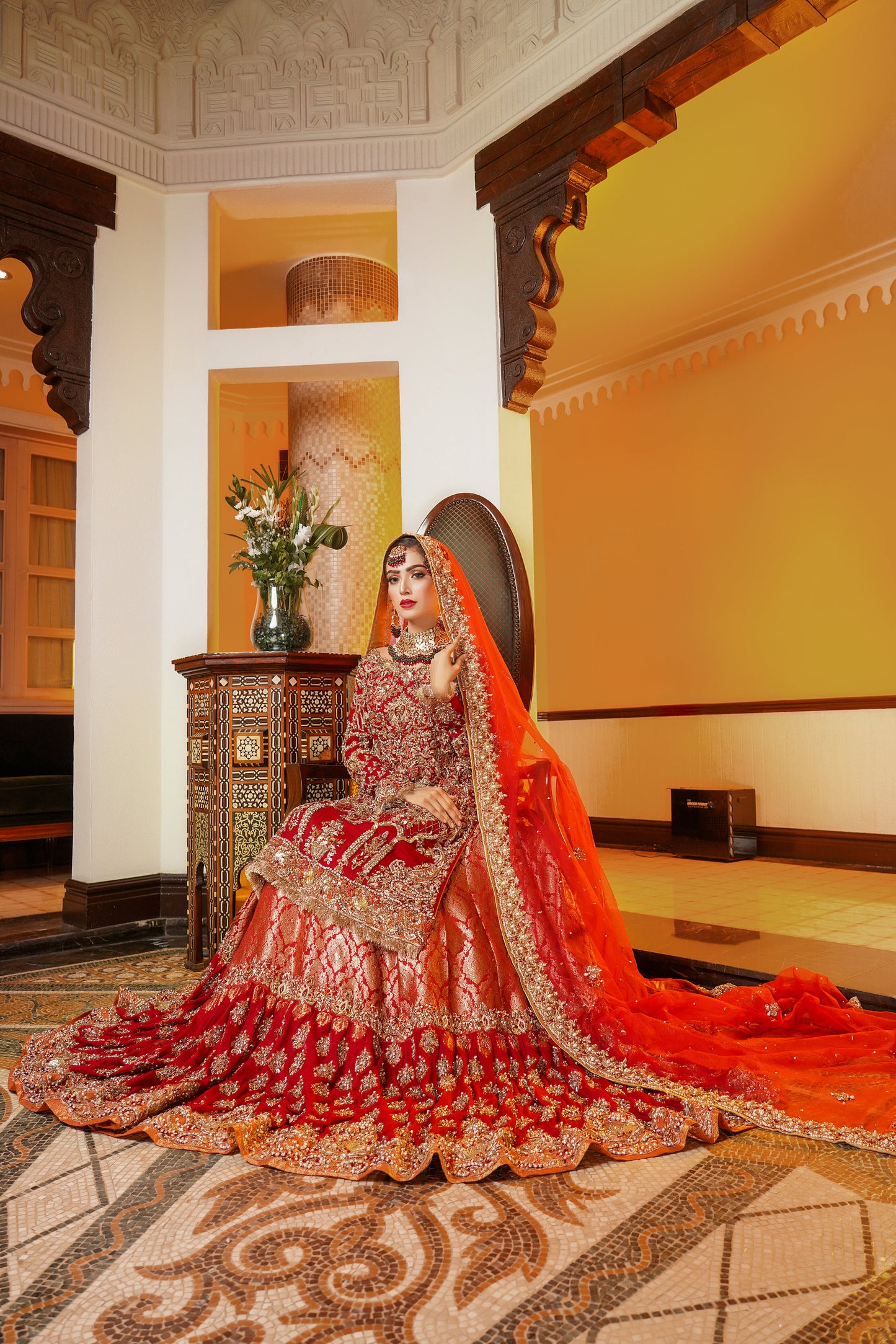 Red and gold Pakistani bridal dress. The dress is a beautiful combination of vibrant red and rich gold. The bodice of the dress features intricate gold embroidery and beadwork, while the skirt is adorned with a heavy gold border. The dress has a fitted bodice with a flared skirt that flows gracefully. The outfit is completed with a matching red dupatta that is embellished with gold embroidery. 