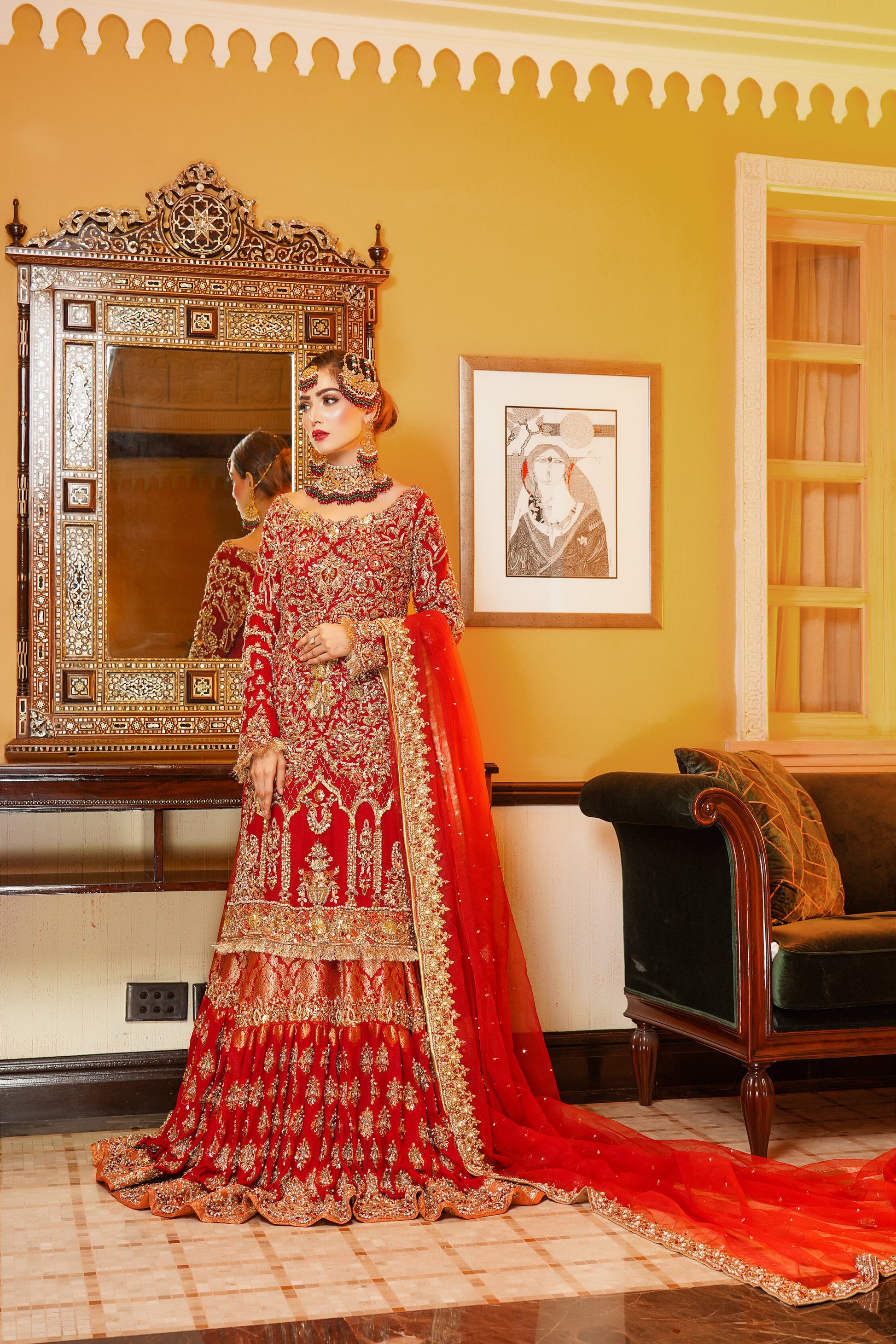 Red and gold Pakistani bridal dress. The dress is a beautiful combination of vibrant red and rich gold. The bodice of the dress features intricate gold embroidery and beadwork, while the skirt is adorned with a heavy gold border. The dress has a fitted bodice with a flared skirt that flows gracefully. The outfit is completed with a matching red dupatta that is embellished with gold embroidery. 