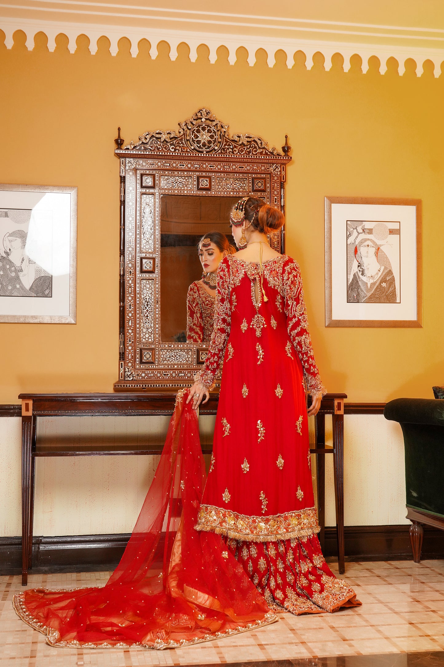 Red and gold Pakistani bridal dress. The dress is a beautiful combination of vibrant red and rich gold. The bodice of the dress features intricate gold embroidery and beadwork, while the skirt is adorned with a heavy gold border. The dress has a fitted bodice with a flared skirt that flows gracefully. The outfit is completed with a matching red dupatta that is embellished with gold embroidery. 