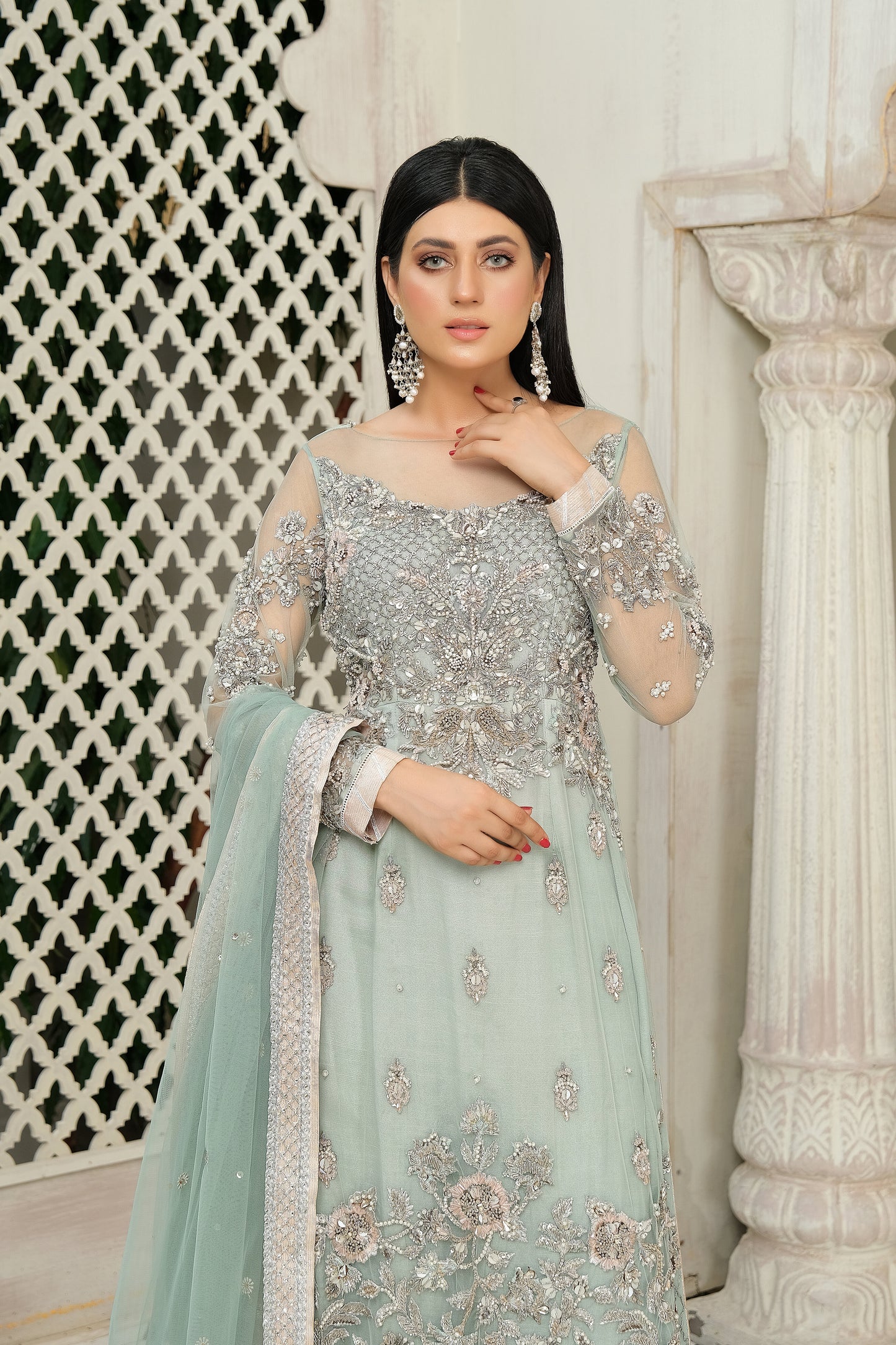 A stunning combination of blue and silver embroidery on a flowing bridal gown. The intricate silver work adorns the bodice and cascades down to the hemline, while the blue fabric provides a beautiful backdrop. The dress also features a flowing dupatta with delicate silver details, completing the elegant bridal look.