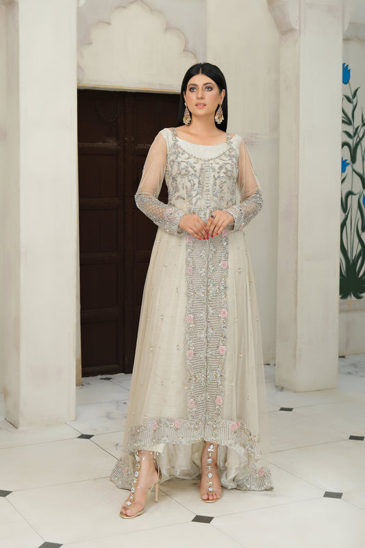 light nude Pakistani formal dress with intricate silver work. The dress features delicate embroidery, sequins, and other hand-crafted designs that create a unique and beautiful pattern on the fabric. It has a long, flowing silhouette that drapes beautifully on the body and full-length sleeves with silver work detailing. The neckline is also adorned with silver work embellishments, adding glamour and sophistication to the dress.